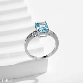 925 sterling silver ring featuring a radiant-cut blue topaz stone with side zirconia accents, shown on hand and in elegant close-up angles