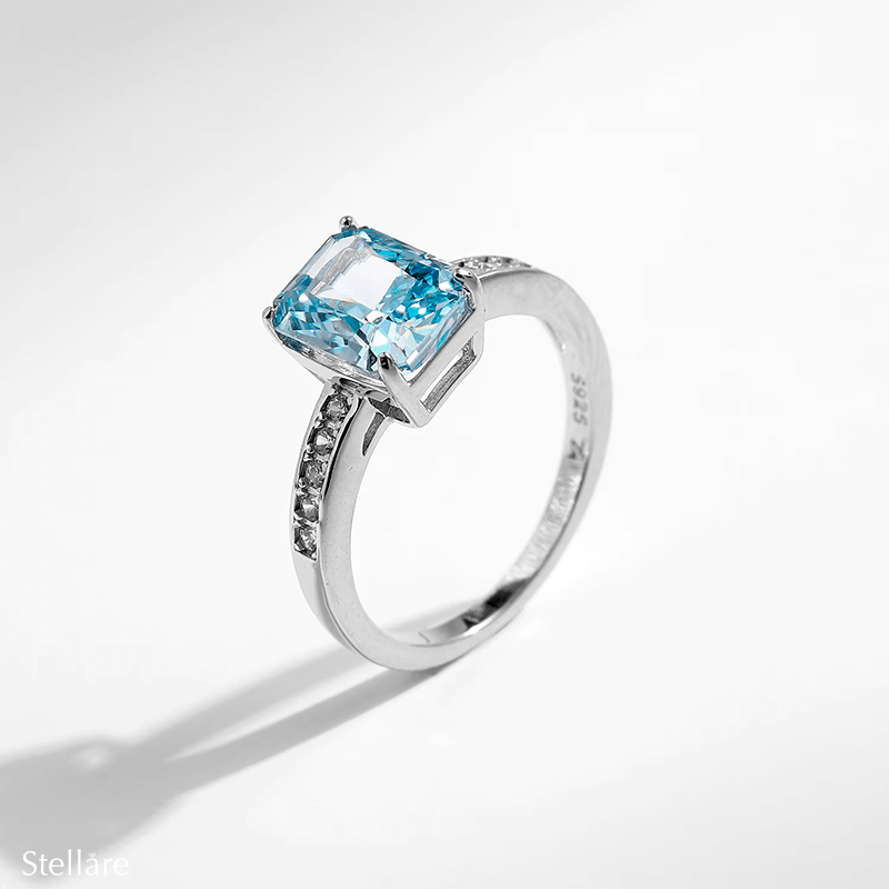 925 sterling silver ring featuring a radiant-cut blue topaz stone with side zirconia accents, shown on hand and in elegant close-up angles