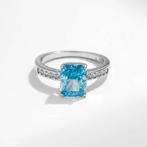 925 sterling silver ring featuring a radiant-cut blue topaz stone with side zirconia accents, shown on hand and in elegant close-up angles
