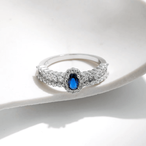 925 sterling silver ring featuring a deep blue oval sapphire and a triple row of shimmering zirconia stones, styled on hand and in detail